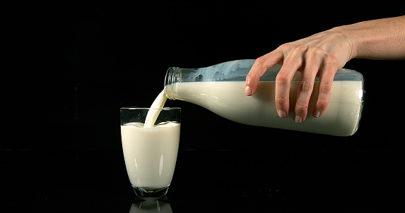Milk being poured into Glass against black Background
