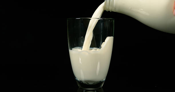 istock Milk being poured into Glass against black Background 1658932501