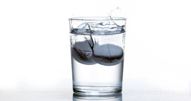 istock Tablets Falling and Dissolving into a Glass of Water against White Background 1658938853