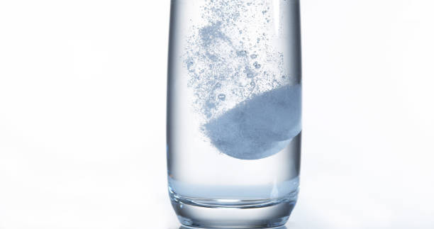 istock Tablets Falling and Dissolving into a Glass of Water against White Background 1658938858