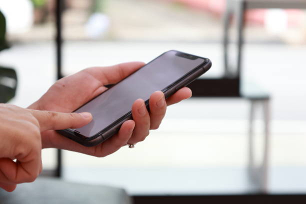 istock Female hand using phone, holding mobile phone, hand using smartphone 1658939972