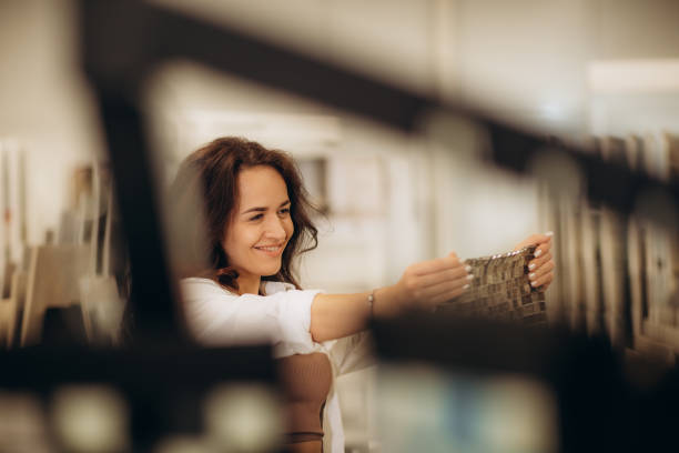 a woman chooses a tile using a tile catalog in a store.