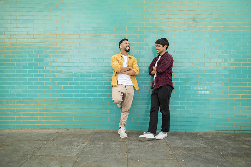 two men talking on the street on blue wall background - lgbt gay concept -