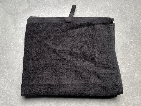 Black folded cotton towel on the granite tile background