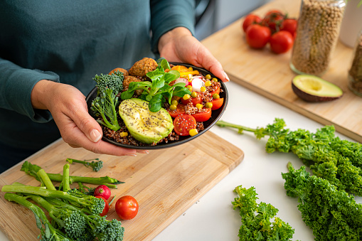 Close up of woman's hands holding a healthy plant-based salad plate. Healthy eating concept. High resolution 42Mp indoors digital capture taken with SONY A7rII and Zeiss Batis 40mm F2.0 CF lens
