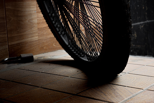 A bicycle wheel on the garage floor, a bicycle parked in the garage.