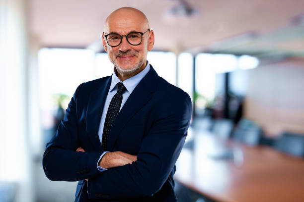 Portrait of confident businessman standing at the office Portrait of confident businessman at the office. Mid aged professional man wearing suit and tie. Copy space. bald guys with beards stock pictures, royalty-free photos & images
