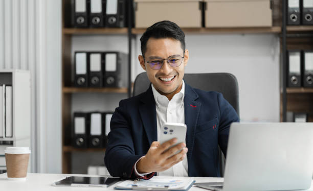istock Smiling Asian young freelancer working from home remotely.He is talking on the phone. 1658970978