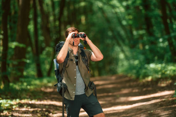 istock Looking through the binoculars. Tourist in summer forest. Conception of exploration and leisure 1658972648