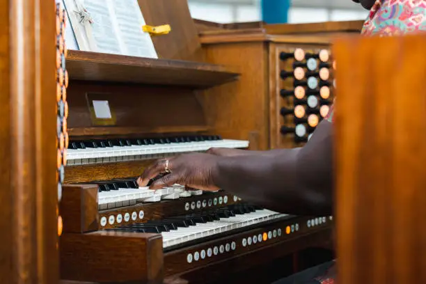 Beautiful brown wooden viscount organ with three layers played by a black man
