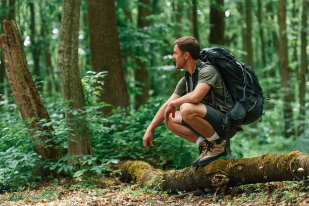 istock Sitting on the fallen tree. Tourist in summer forest. Conception of exploration and leisure 1658975487