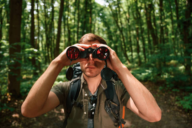 istock Looking through the binoculars. Tourist in summer forest. Conception of exploration and leisure 1658976517