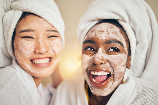 Skincare, face and women friends in a bedroom with mask, application and spa day bonding in their home. Beauty, cream and people with self care sleepover, facial or cosmetic wellness on the weekend