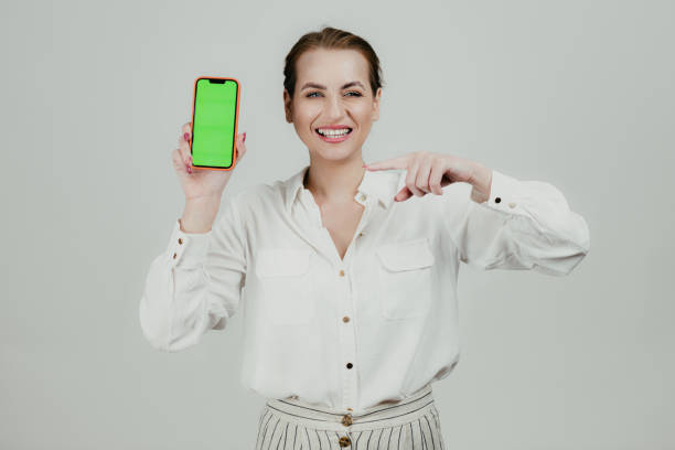 istock Smiling woman holding a smartphone with a green screen 1658982079