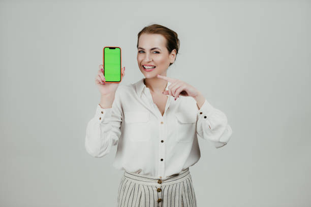 istock Smiling woman holding a smartphone with a green screen 1658982086