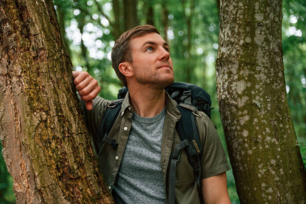 istock Standing between the trees. Tourist in summer forest. Conception of exploration and leisure 1658986492
