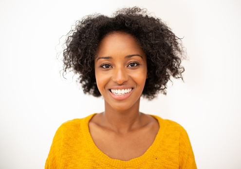 Close up portrait of smiling young african american woman with curly hair against white background