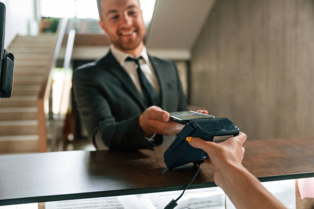 istock Wireless payment by using phone and terminal. A man in a black jacket at the hotel reception 1659002854