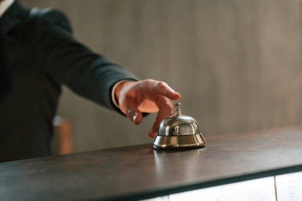 istock Close up view, using hotel desk bell. A man in a black jacket at the hotel reception 1659003413