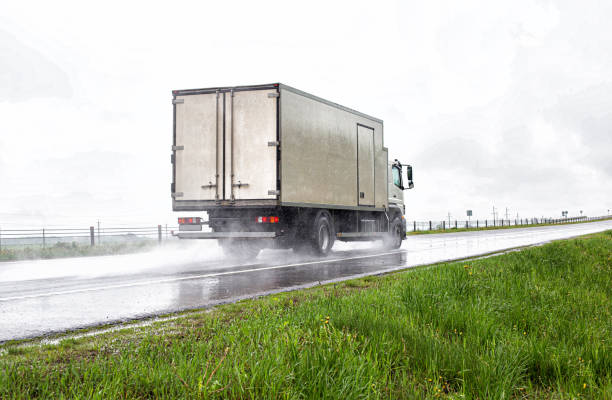 A truck with a semi-trailer transports cargo in the summer on a motorway in rainy weather. Copy space for text A truck with a semi-trailer transports cargo in the summer on a motorway in rainy weather, industry truck rain stock pictures, royalty-free photos & images
