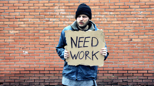 Homeless holds piece of cardboard with inscription Need Work. Refugee is at brick wall looking for job. Male tramp in dirty clothes. Below poverty line. Bearded fugitive beggar. Immigrant. Drunkenness Consequences of drunkenness, alcoholism. Male caucasian refugee in hat cap is in foreign country because of war in his own country. Illegal immigrant stands at brick wall looking for job. Tramp in dirty clothes. Below poverty line. Bearded fugitive. Pauper Beggar. Cowboy Shot unemployment stock pictures, royalty-free photos & images