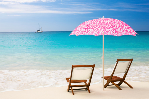 two teak chairs and pink polka dot umbrella at a perfect beach in St. John, US Virgin Islands