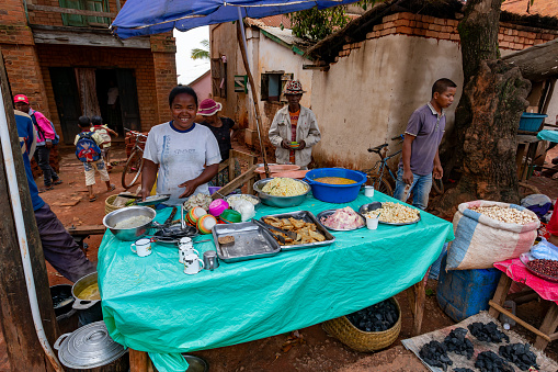 Mandoto, Madagascar - November 9th, 2022: Street market in Mandoto city, with vendors and ordinary people shopping and socializing. Woman sell local special food.