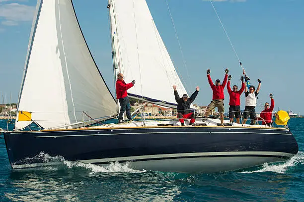 Side view of sailboat racing at regatta, six crew members celebrating the first place, Adriatic sea, Croatia,Europe