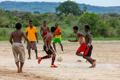 BEKOPAKA, MADAGASCAR - NOVEMBER 6, 2022: A group of young men play soccer on a dirt field in Bekopaka, a rural village in western Madagascar. The game is a popular pastime among the local people.