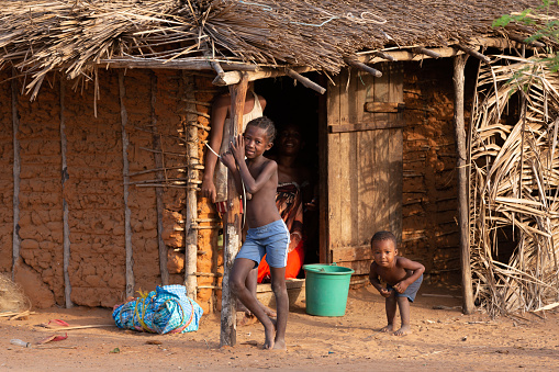 three african children in a village near Kalahari desert, the sister feeding her brother in the outdoors kitchen