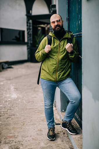 Portrait of a handsome bearded man with a backpack in the city street on a lovely autumn day in Thessaloniki