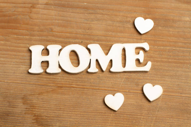 A home sign with white hearts on a wooden background with copy space