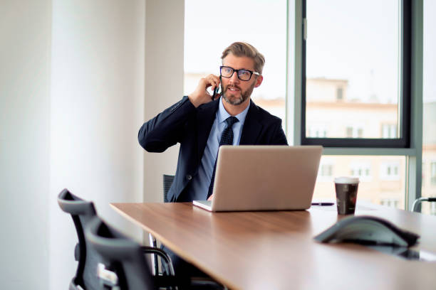 istock Businessman sitting in a modern office and using mobile phone and laptop for work 1659079611