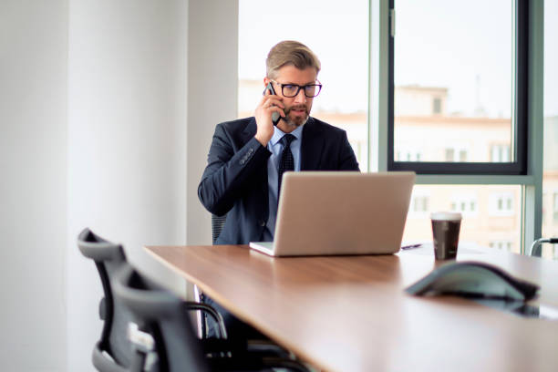 istock Businessman sitting in a modern office and using mobile phone and laptop for work 1659079615