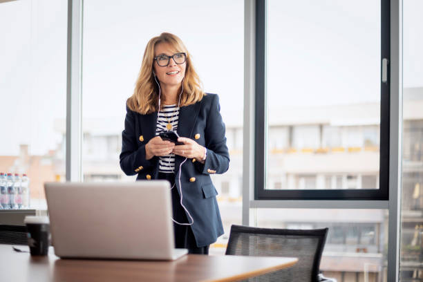 istock Confident professional woman using earphone and smartphone and having video call in a modern office 1659080150