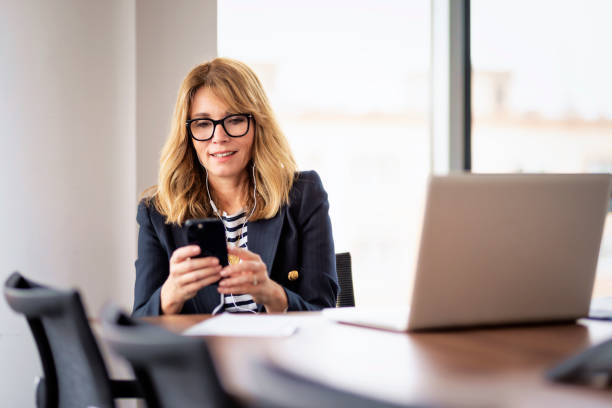 istock Confident professional woman using earphone and smartphone and having video call in a modern office 1659080154