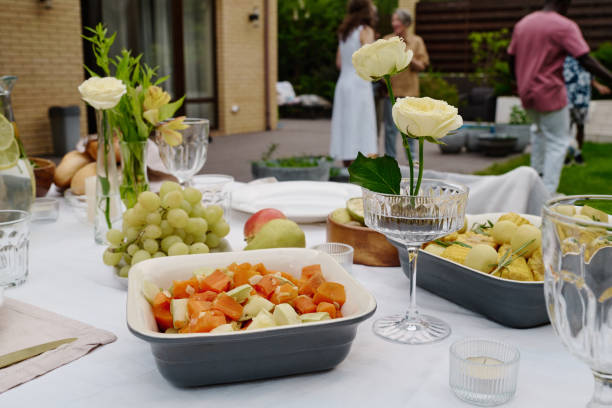 Tray with appetizing vegetable stew standing among vases with white roses