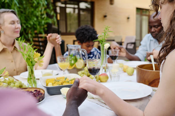 Focus on hands of young intercultural couple blessing food on served table