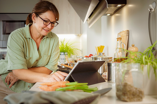 Woman gets online recipe from digital tablet to cook healthy meal. High resolution 42Mp studio digital capture taken with SONY A7rII and Zeiss Batis 40mm F2.0 CF lens