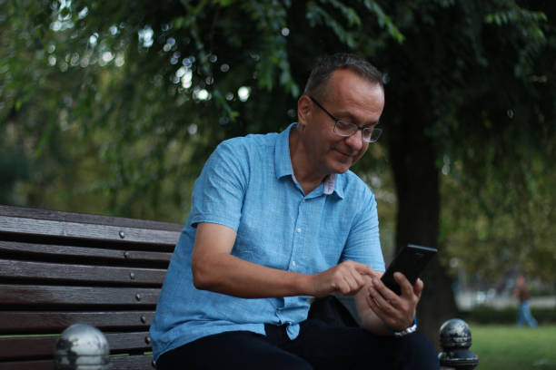 istock Elegance mature man on bench using phone 1659101999