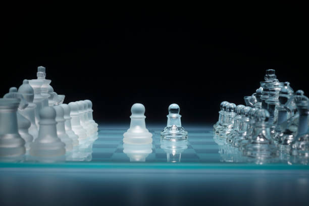 istock clear glass chess figures arranged in a row reflecting in glass chessboard. Isolated on black 1659106368