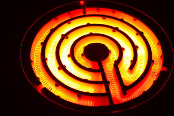istock Coiled heating wire of a retro electric stove heated bright red (nichrome wire, black background photo) 1659124565