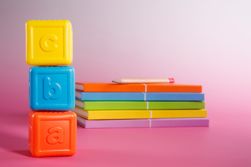 A stack of books with some toy alphabet blocks