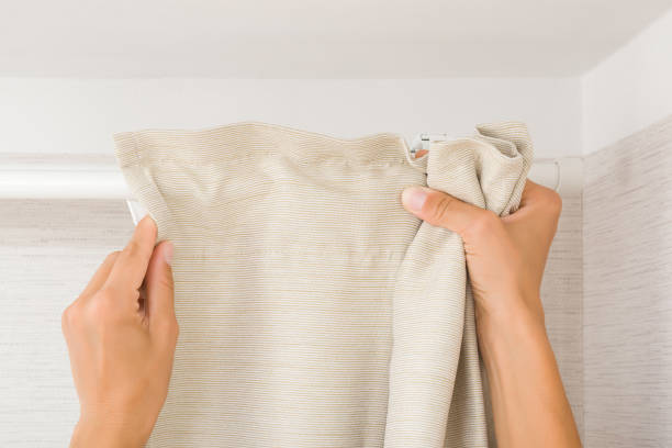 Young adult woman hands hanging clean beige thick night curtains on white rod at home room. Closeup. Point of view shot. Young adult woman hands hanging clean beige thick night curtains on white rod at home room. Closeup. Point of view shot. curtain rail stock pictures, royalty-free photos & images