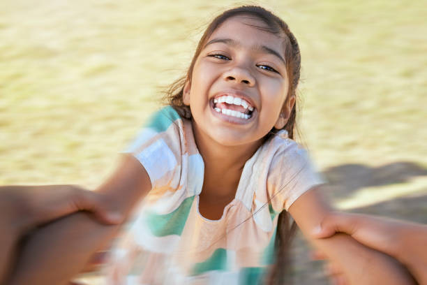 cara de niña feliz balanceándose y girando en círculos por los brazos en el parque con su padre. lindo niño juguetón que se divierte, ríe y sonríe mientras se une a un padre en un verano soleado al aire libre - personal perspective togetherness child swinging fotografías e imágenes de stock