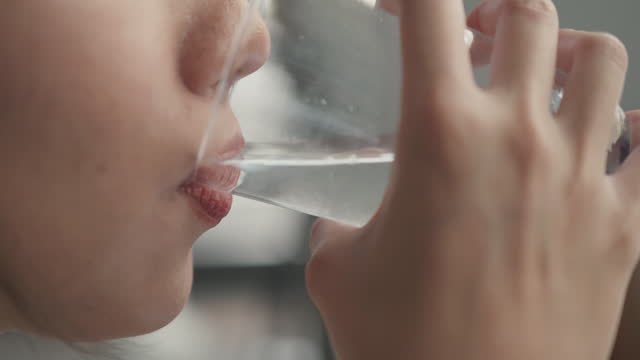 Close-up shot of Woman drinking water from a water glass.