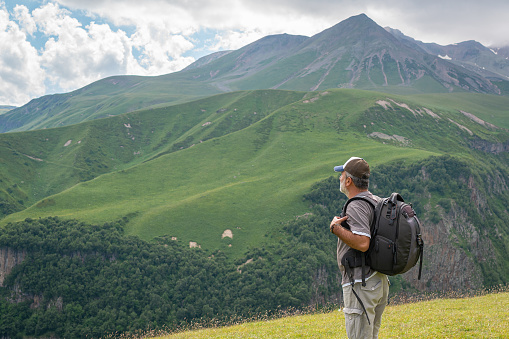 Mature man watching the Caucasus Mountains view on a sunny day Kazbegi,Georgia