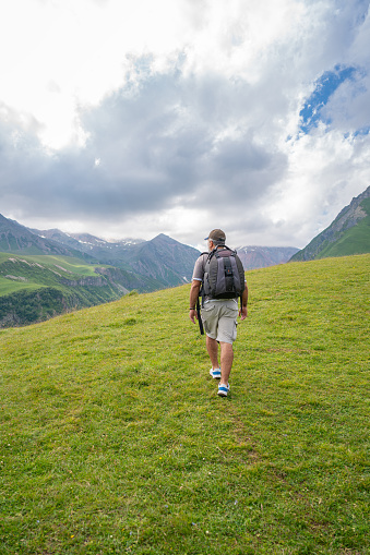 Mature man hiking at the valley of Caucasus mountains at sunny day