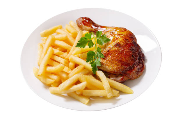 plate of baked chicken leg with french fries on white background stock photo