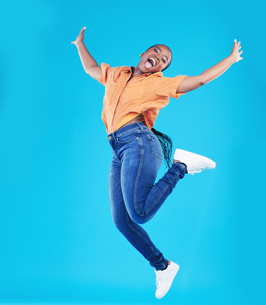 Jump, black woman and excited portrait with motivation in studio from celebration smile. Happy, energy and African female person with promotion and blue background with leap from deal announcement